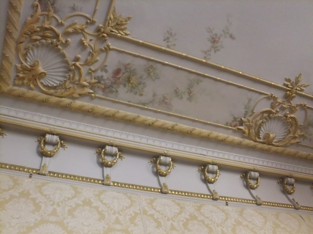 A Victorian-era moulded frieze, painted in tones of peach and gold and decorated with floral motifs.